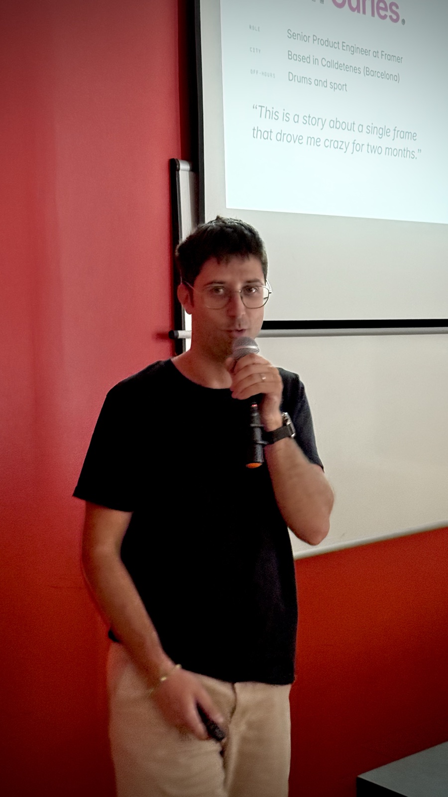 Carles Núñez parlant amb un micròfon davant de la projecció de la seva xerrada