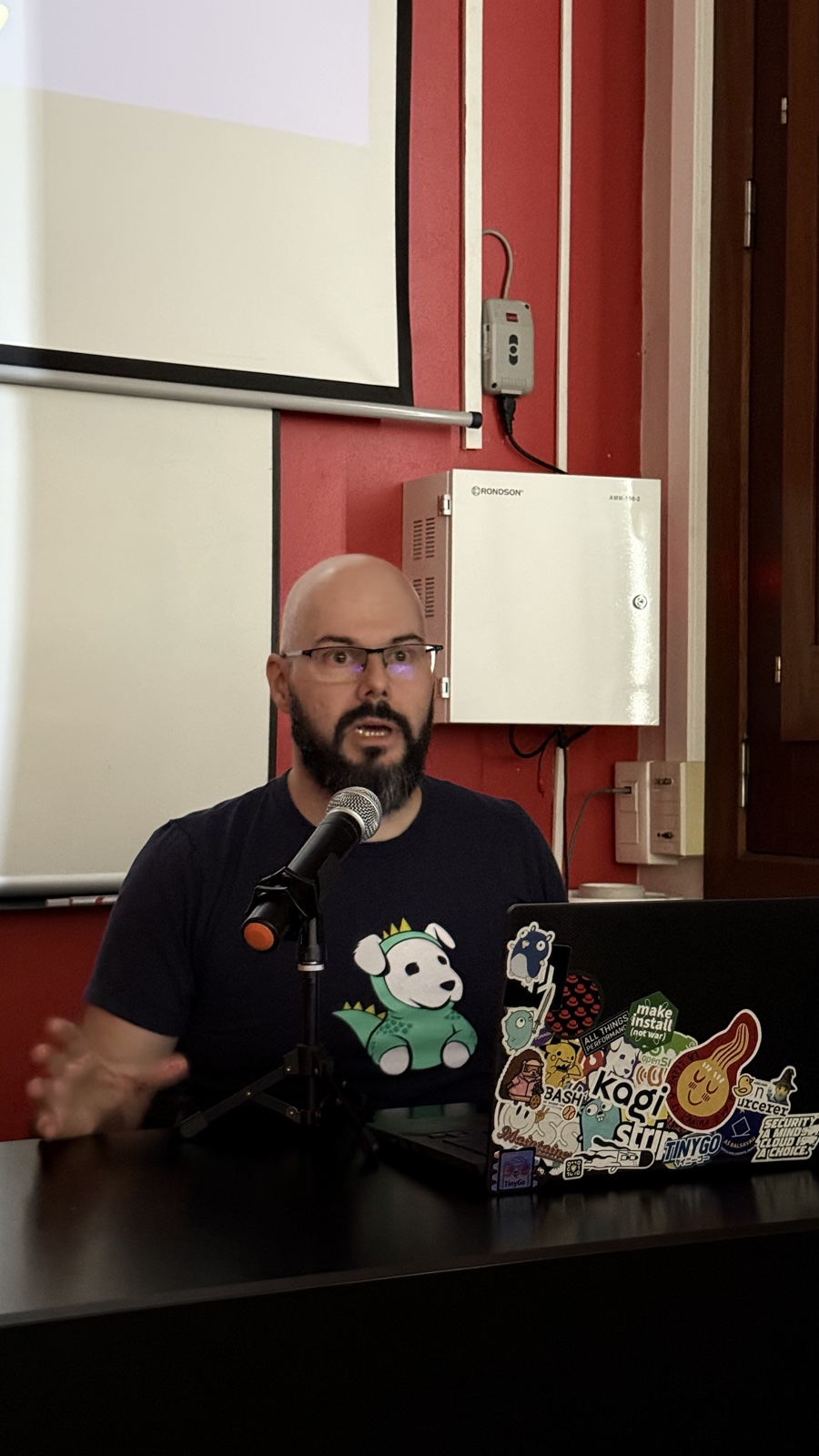 Darío Castañé parlant, assegut davant d’un micròfon i el seu portàtil durant la seva xerrada