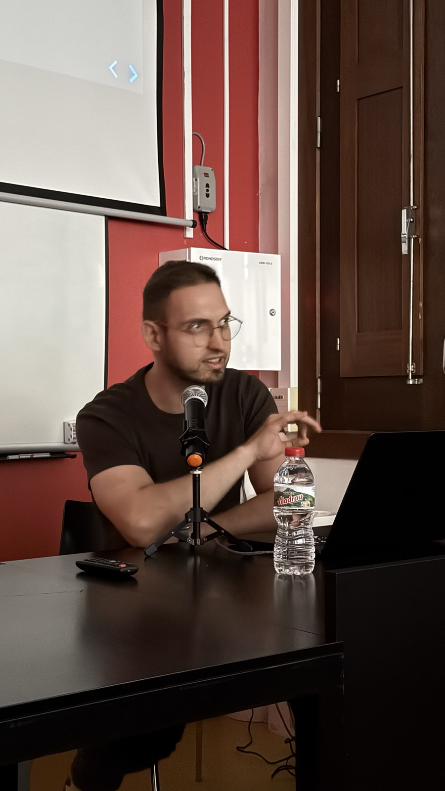 Luis Castro parlant, assegut davant d’un micròfon i un portàtil durant la seva xerrada